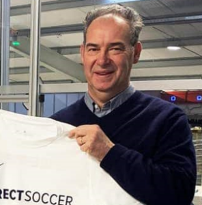 A photo of Bryce Gibson, Owner of Direct Soccer, holding a Direct Soccer T-shirt