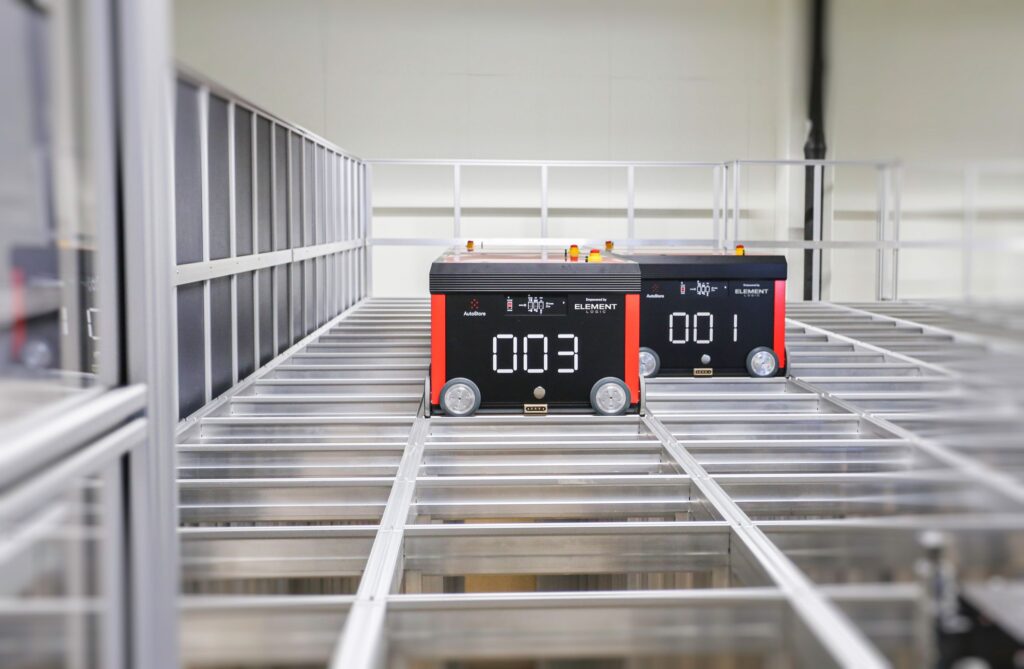 Two robots are working on top of an AutoStore grid.