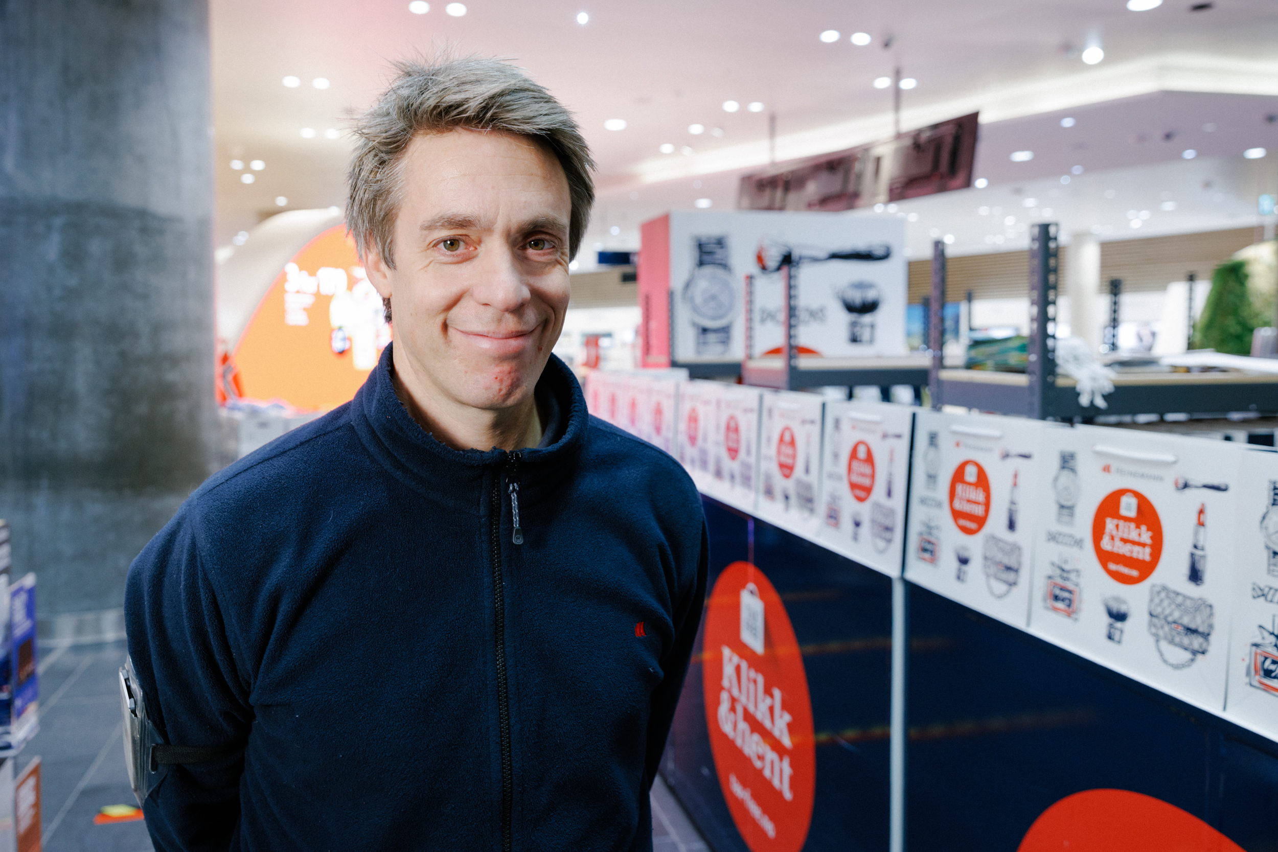 Øyvind Andersen standing in from of the Click and collect station out in the store, smiling to the camera.