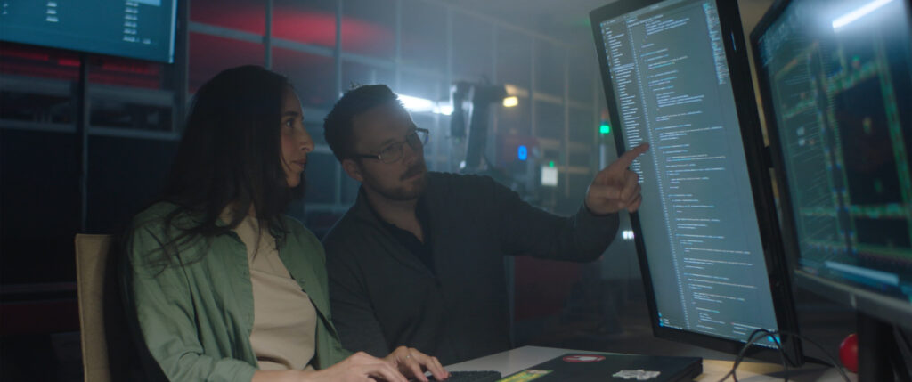 Two people talking looking at code on a computer screen