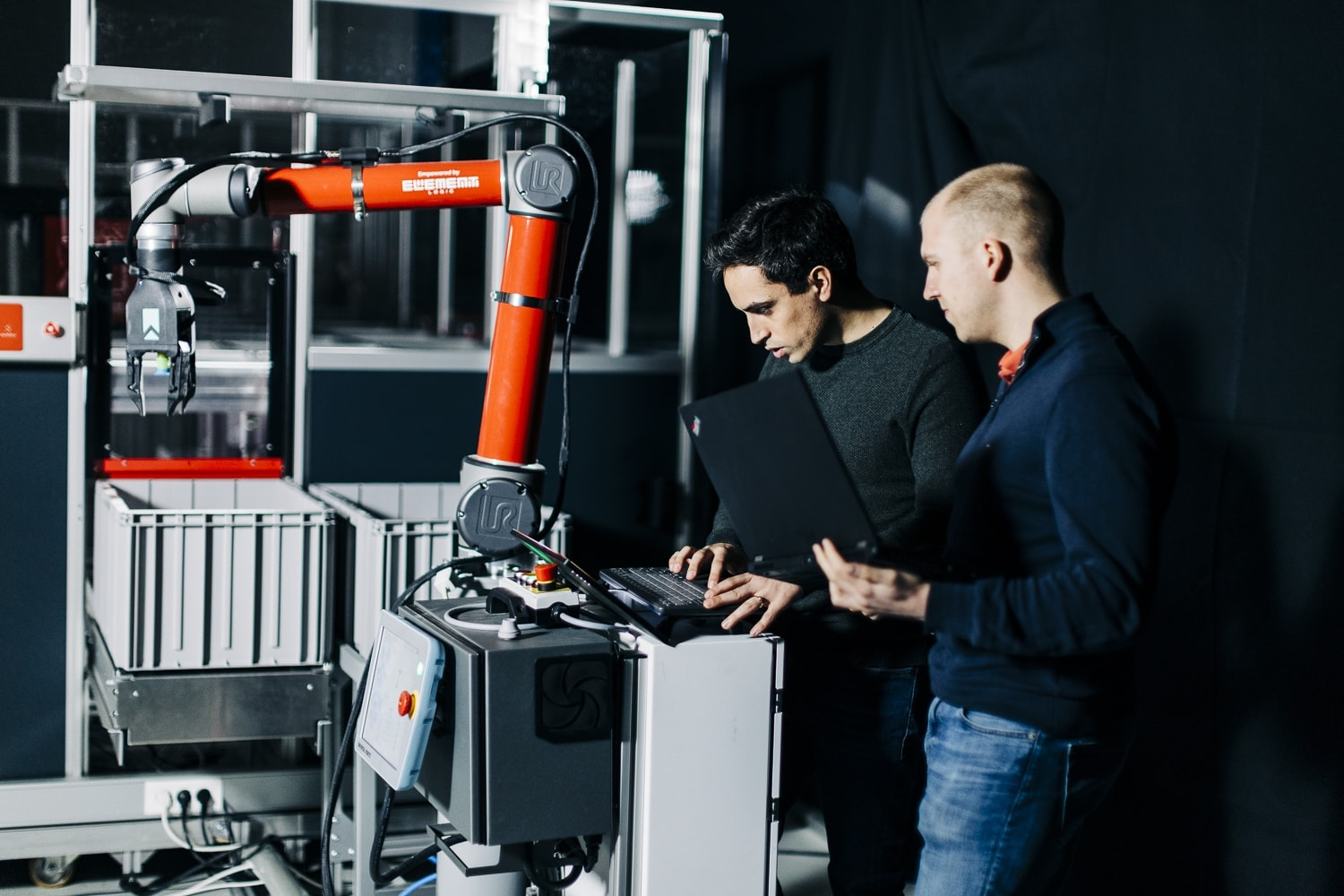 Two men testing a robotic arm