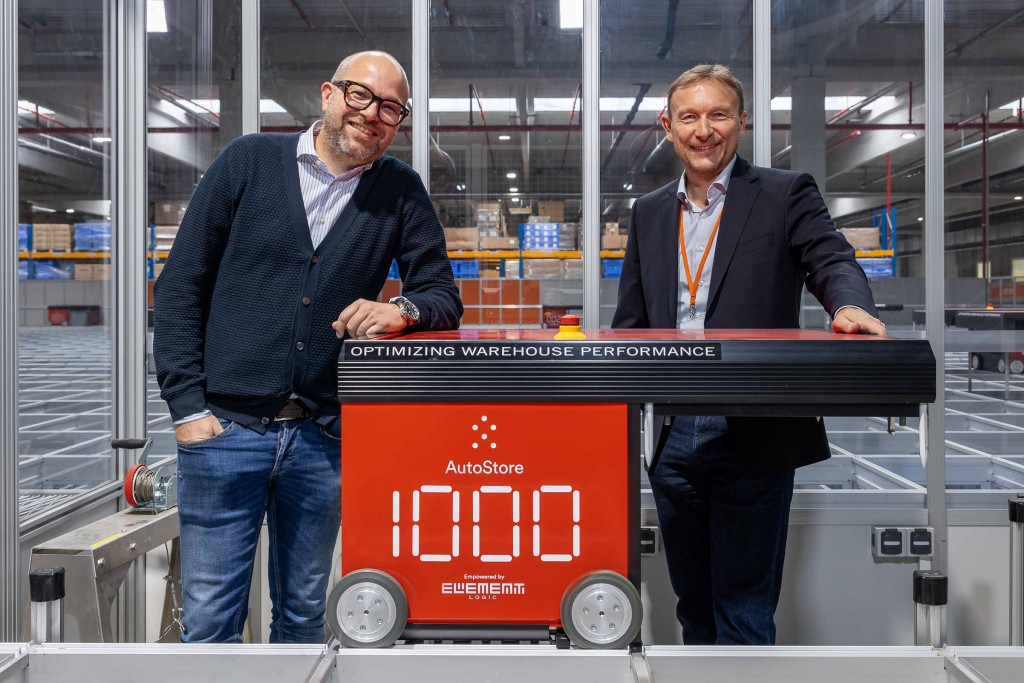 Two men on each side of an autostore robot