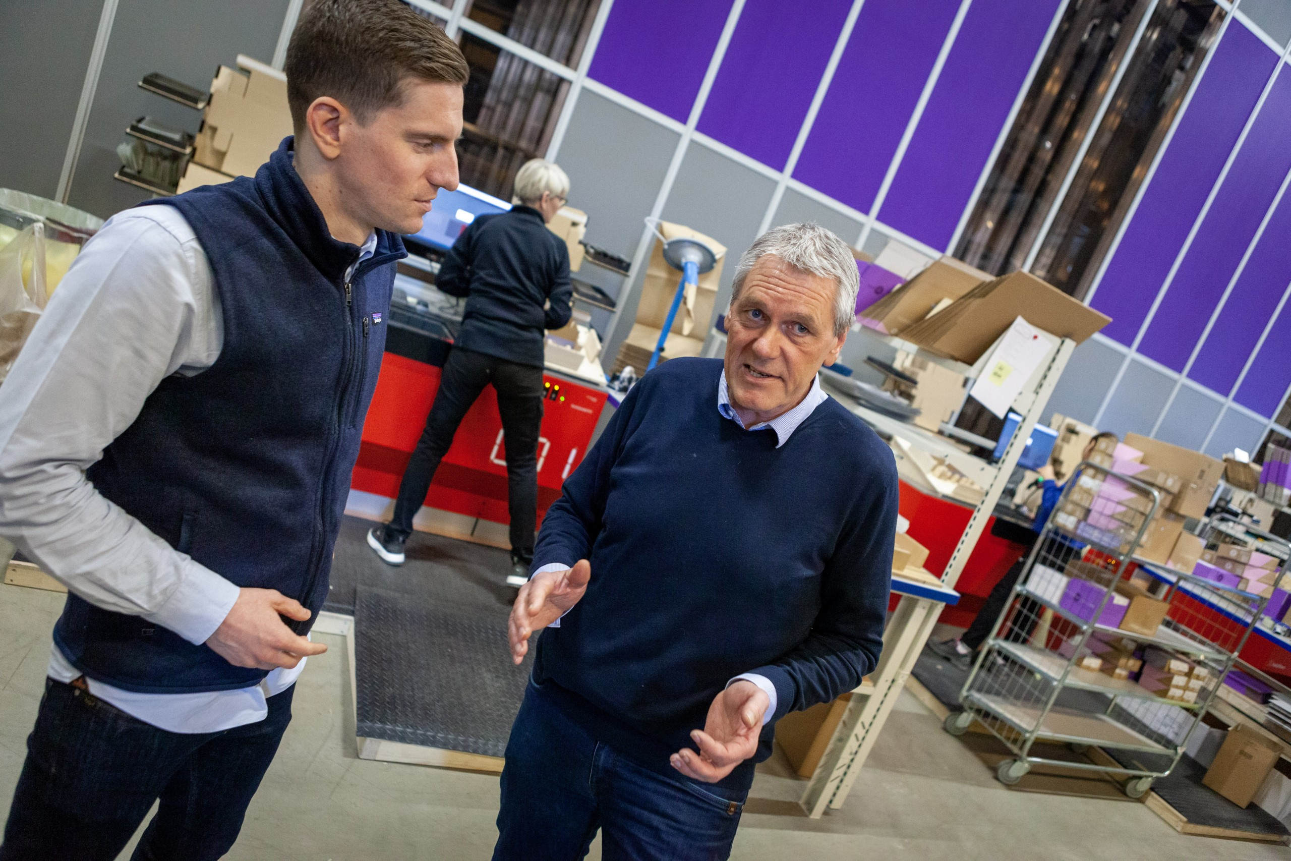 Two men talking in front of an automated warehouse