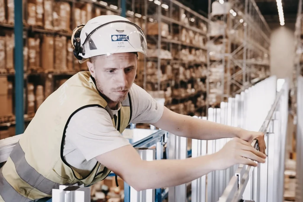 Un hombre con casco y chaleco amarillo está construyendo la cuadrícula del AutoStore.