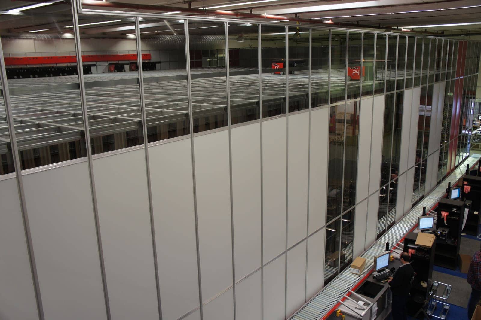 The Elektroskandia AutoStore system with employees working at the picking stations with conveyor belts.