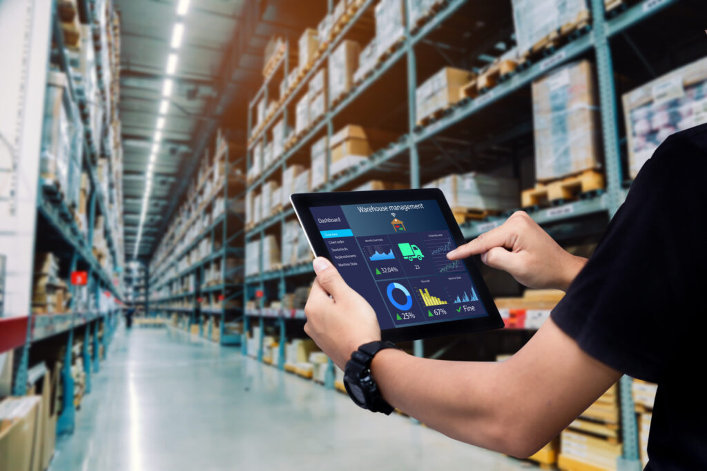 man with a tablet looking at data inside of a warehouse.