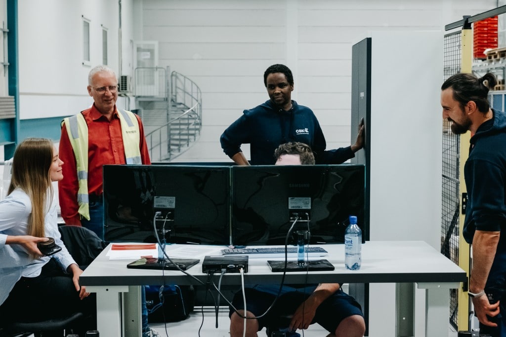 Fünf Personen arbeiten vor einem Computer zusammen, um die Bedienung des AutoStore-Systems zu erlernen.